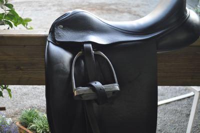 black dressage saddle on a railing