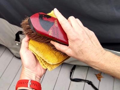 horse brush being wiped on a damp cloth