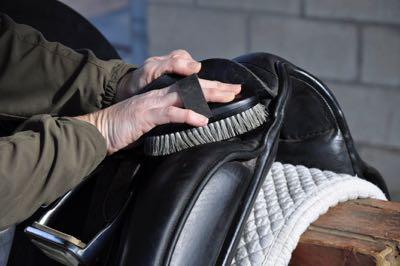 using a small finishing brush to clean a dressage saddle