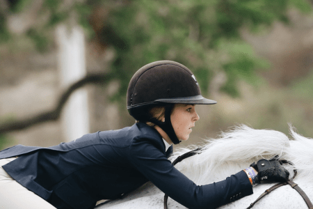 girl jumping a horse wearing a helmet